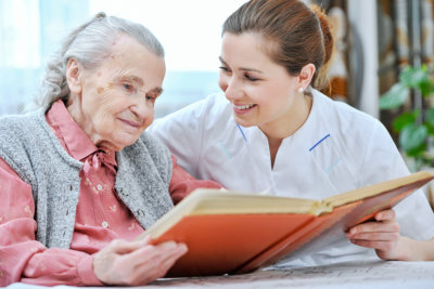 senior woman and caregiver reading book